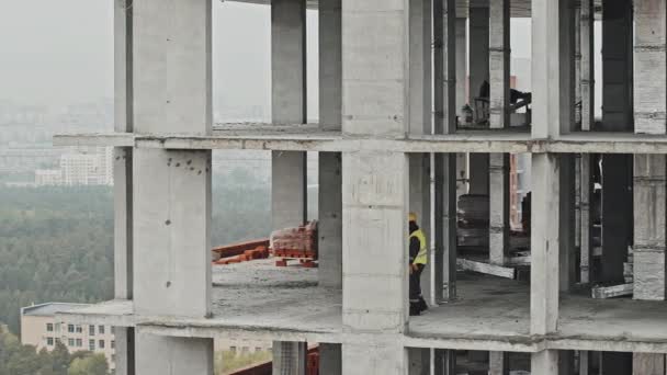 建設中の建物の下を歩いている労働者の2人の民族的に多様な男性の長いショットをパン何かを議論 — ストック動画