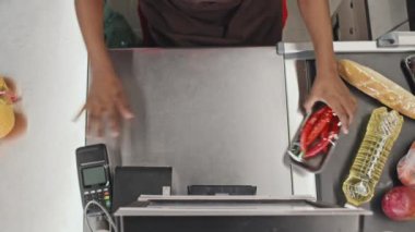 Süpermarkette müşterilere hizmet veren kasiyerin üst görünümü, tarama ve tartma