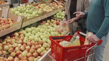 Büyük süpermarketin üretim bölümünde taze meyve alan tanınmayan birkaç müşterinin görüntüsü.