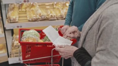 Marketten yiyecek alırken alışveriş listesini kontrol eden olgun beyaz bir çift.