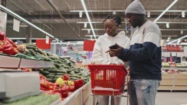 Genç Kara Çift süpermarketteki üretim departmanından taze sebze seçip alıyor.