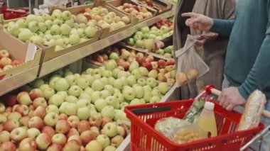 Büyük süpermarketin üretim departmanından taze meyve seçen ve alan birkaç müşteri.