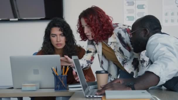 年轻的白人妇女和黑人男子帮助他们的同事用手提电脑解决文档中的数据问题 — 图库视频影像