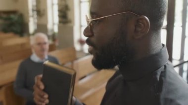 Afrika kökenli Amerikalı Katolik rahibin kilise ayini sırasında İncil 'den bahsettiği seçici yakın çekim.