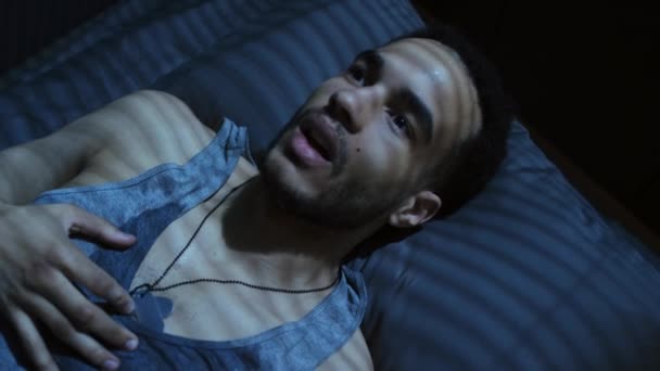 悪夢の後にパニック発作を起こしてベッドの上に横たわっている若い黒軍の男の高い角度のビューのクローズアップ — ストック動画