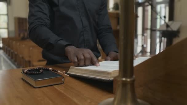 低视角拍摄的非裔美国天主教牧师站在教堂祭坛前祈祷 — 图库视频影像