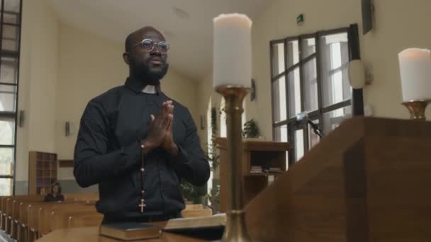非洲裔美国牧师 手腕上有念珠 站在教堂祭坛前向上帝祈祷的低角度中镜头 — 图库视频影像