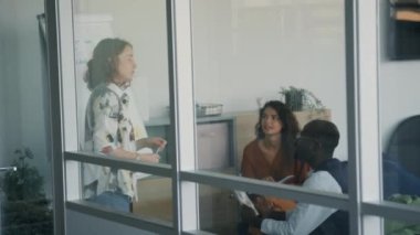 Modern ofiste yeni bir iş projesi üzerinde çalışan üç farklı gencin cam duvar çekimleri sayesinde.