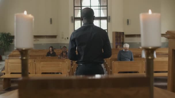 アフリカ系アメリカ人のカトリック聖職者がカトリック教会の人々に説教する様子 — ストック動画