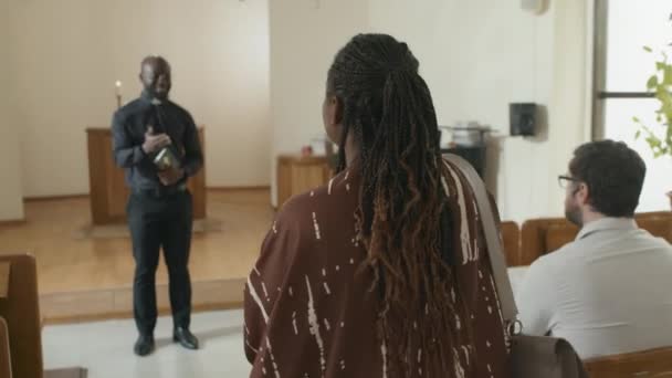 跟随年轻的非洲裔美国妇女在教堂向牧师致意 入座和打开祈祷簿的镜头 — 图库视频影像