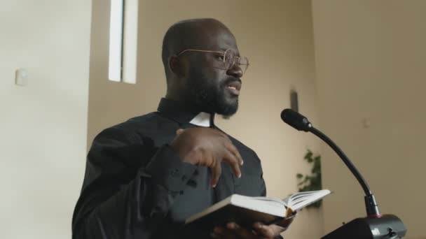Сучасний Молодий Афроамериканський Священик Який Тримає Біблійну Книгу Перед Лектерном — стокове відео