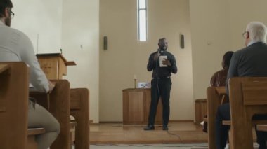 Genç Afrikalı Amerikalı papazın elinde dijital tablet ve mikrofon tutarak kilisedeki cemaate vaaz verdiği uzun vadede Dolly.
