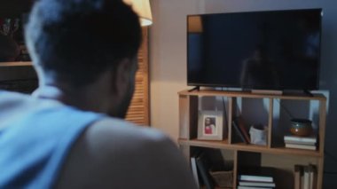 Depresyon geçiren genç adamın seçici odağı TV ekranındaki yansımasına bakıyor ve geceleri bira içiyor.