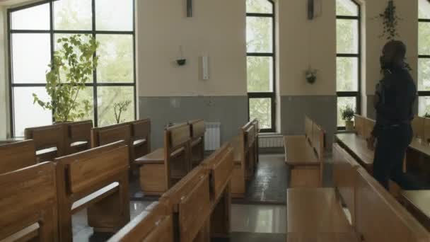 Długie Ujęcie Młodego Afroamerykanina Katolickiego Księdza Trzymającego Modlitewnik Idącego Wzdłuż — Wideo stockowe