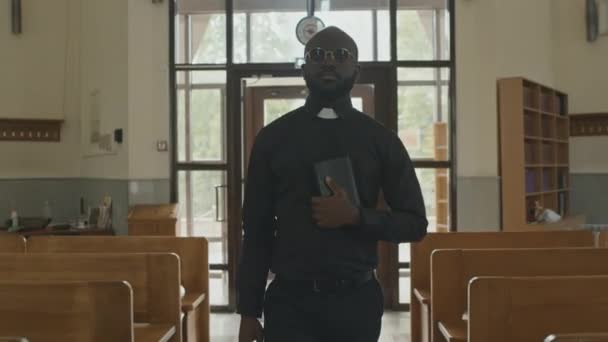 Średniej Jakości Zdjęcie Przystojnego Młodego Afroamerykanina Katolickiego Księdza Okularach Trzymającego — Wideo stockowe