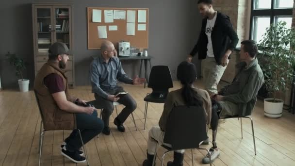 Anak Muda Memasuki Ruang Dan Duduk Kursi Psikoterapis Dan Anggota — Stok Video