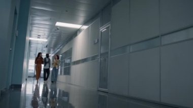 Düşük açıyla bakan genç adam ve kadınların ofis koridorunda bir şeyler hakkında sohbet ederken görüntüsü.