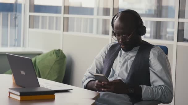 Μεσαίο Πορτρέτο Του Αφροαμερικανού Άνδρα Φορώντας Ακουστικά Κάθεται Στο Γραφείο — Αρχείο Βίντεο