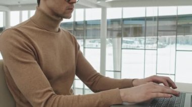 Gözlüklü ciddi bir ofis çalışanının modern ofisteki dizüstü bilgisayarına yoğunlaşması.