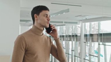 Genç iş adamı, iş arkadaşıyla birlikte akıllı telefondan çalışma anlarını tartışıyor.