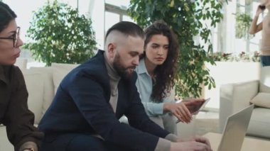 Toplantı sırasında dizüstü bilgisayarla çalışan bir grup genç iş adamının orta ölçekli görüntüsü.