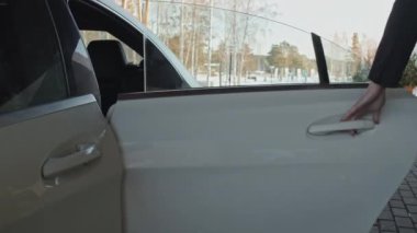 Takım elbiseli adam iş adamına arabanın arka kapısını açıyor. İş seyahatini arabayla yapıyor.