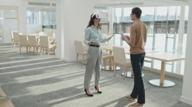 Genç iş kadını, dijital tabletle bağlantı kuran işadamının gözlükleriyle sanal gerçekliği test ediyor.