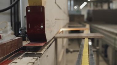 Erkek işçinin mobilya fabrikasındaki lazer kesme makinesine tahta koyduğu yakın çekim.