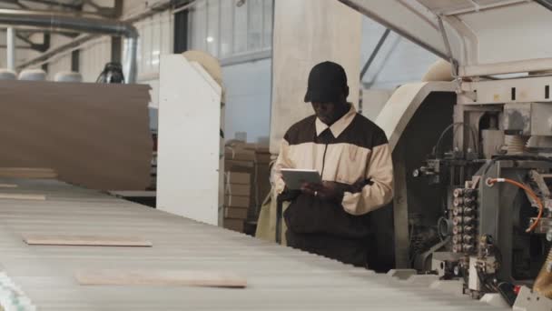 Afroamerykanski Technik Uzywajacy Tabletu Cyfrowego Podczas Kontroli Drewnianych Desek Taśmie — Wideo stockowe