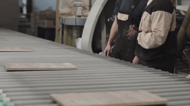 Strzał Śledzący Pracowników Omawiających Drewniane Deski Przenośniku Taśmowym Fabryce Mebli — Wideo stockowe