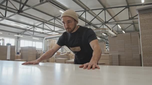 家具製造工場で働きながら板を機械に押し込む男性労働者 — ストック動画