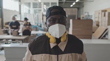 Koruyucu yüz maskesi takmış ve mobilya fabrikasında kamera önünde poz veren Afrikalı Amerikalı işçilerin göğüs portresi.