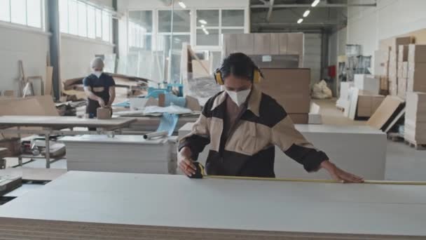 Pracownica Ochronnych Nausznikach Maskach Mierzenia Drewnianej Deski Taśmą Znakowania Podczas — Wideo stockowe