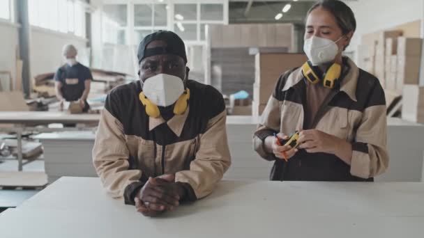 노동자 귀마개와 마스크를 착용하고 아프리카 미국인 동료에게 걸어가서그와 공장에서 카메라 — 비디오