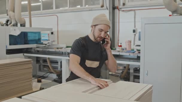 Człowiek Badający Drewniane Deski Mówiący Przez Telefon Komórkowy Podczas Pracy — Wideo stockowe