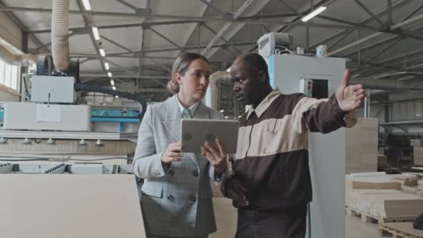 의류를 관리자와 아프리카 미국인 노동자가 공장에서 디지털 태블릿으로 무엇인가를 토론하는 — 비디오