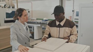 Afrikalı Amerikalı işçi, mobilya fabrikasında çalışırken beyaz kadın yöneticiye ahşap tahtadan bahsediyor.