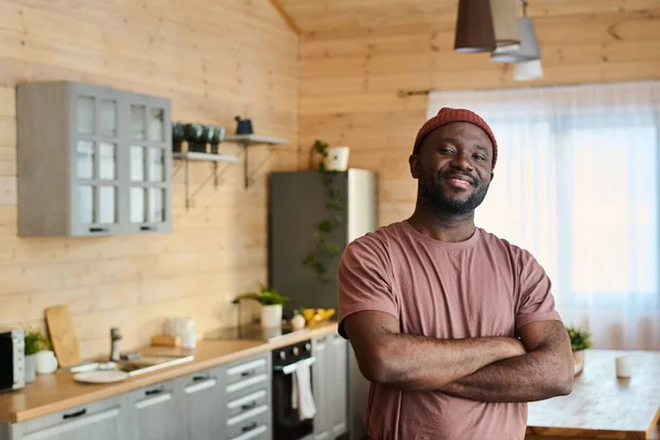 身穿工作服 面带微笑的年轻非裔美国人裁缝师或管道工站在木屋厨房的内部时 看着相机 — 图库照片