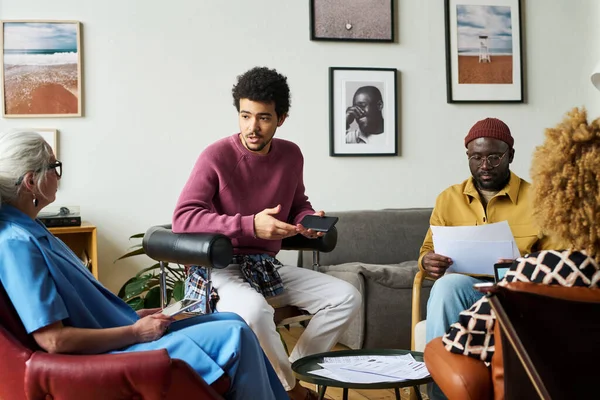 Mladý Multietnický Ekonom Vysvětluje Něco Zralým Kolegyním Když Sedí Kruhu — Stock fotografie