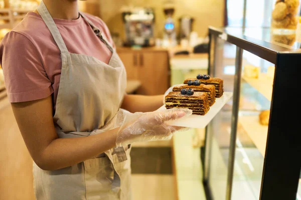 앞치마를 케이크나 디저트를 카페테리아에서 진열품을 꺼내는 장면이 — 스톡 사진