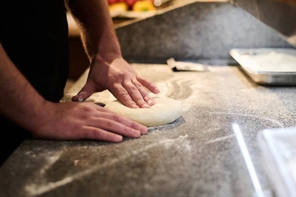 在餐馆准备意大利传统食品时 年轻厨师在桌上揉搓面粉新鲜面团准备披萨的手部特写 — 图库照片