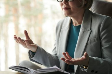 Formalite icabı giyinmiş profesyonel kadın psikoloğu hastaya oturumdaki problemleri açıklarken bir şeyler anlatıyor.