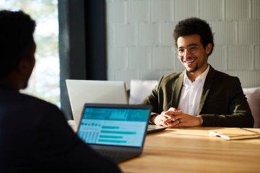 Genç, çok ırklı ve mutlu bir iş adamı. Önünde diz üstü bilgisayarı olan bir meslektaşı var. Toplantının çalışma noktalarını tartışıyorlar.