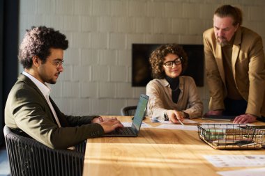 İki yetişkin iş arkadaşının mali belgeleri tartışırken dizüstü bilgisayarda klavye üstüne yazı yazışının yan görüntüsü