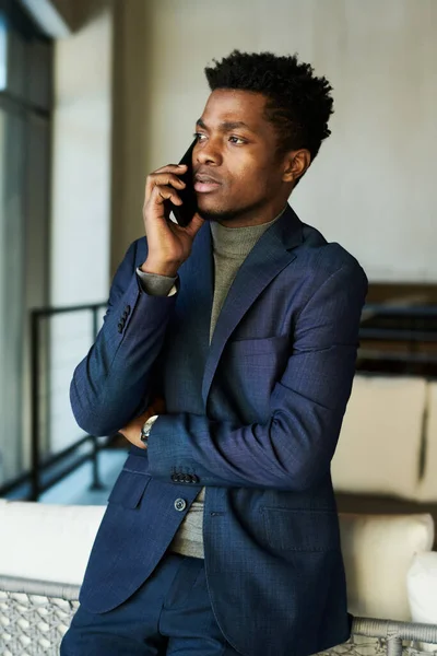 身穿深蓝色西装的年轻而严肃的非裔美国商人站在摄像机前 用智能手机与同事交谈 — 图库照片