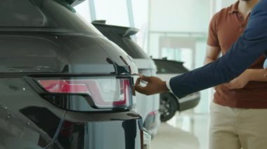 Afro-Amerikalı bir adamın galeri galerisinde çalışırken orta boy bir fotoğrafı müşterilere SUV ya da çapraz bagajı gösteriyor.