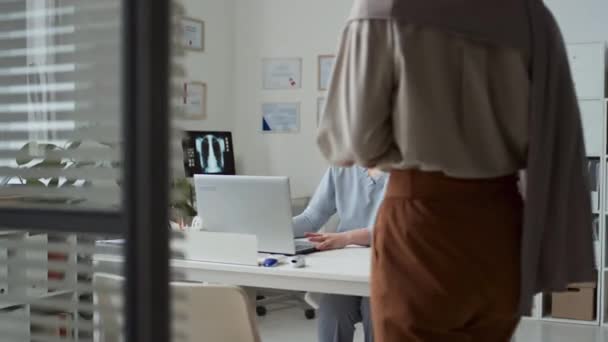 Junge Ärztin Uniform Faltet Laptop Während Muslimische Patientin Hijab Die — Stockvideo