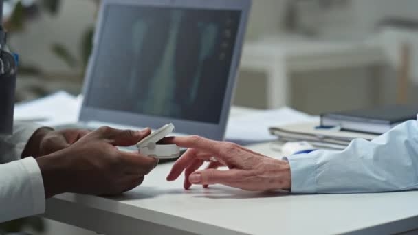非洲裔美国医生在医疗会诊过程中手部近距离放置测量成熟女性患者指尖血饱和度的数字装置 — 图库视频影像