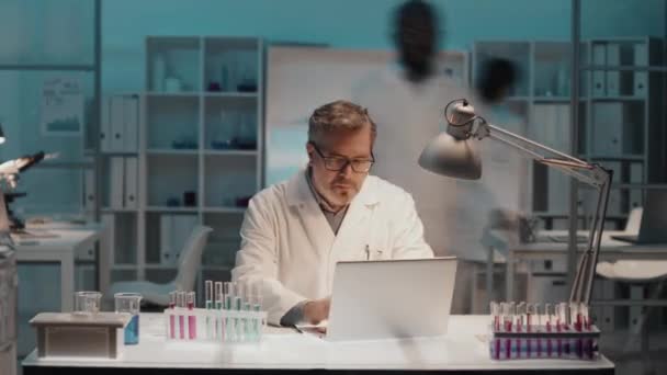 실험실에서 노트북을 사용하여 코트를 노트를 작성하고 액체가 플라스크를 가지고 일하고 — 비디오