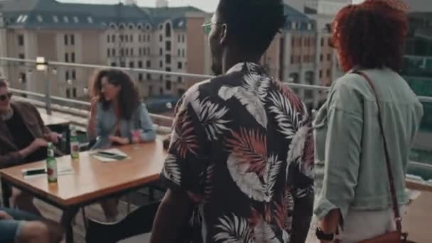 現代の若いアフリカ系アメリカ人男性と女性が屋上でパーティーに参加彼らの友人を迎える — ストック動画